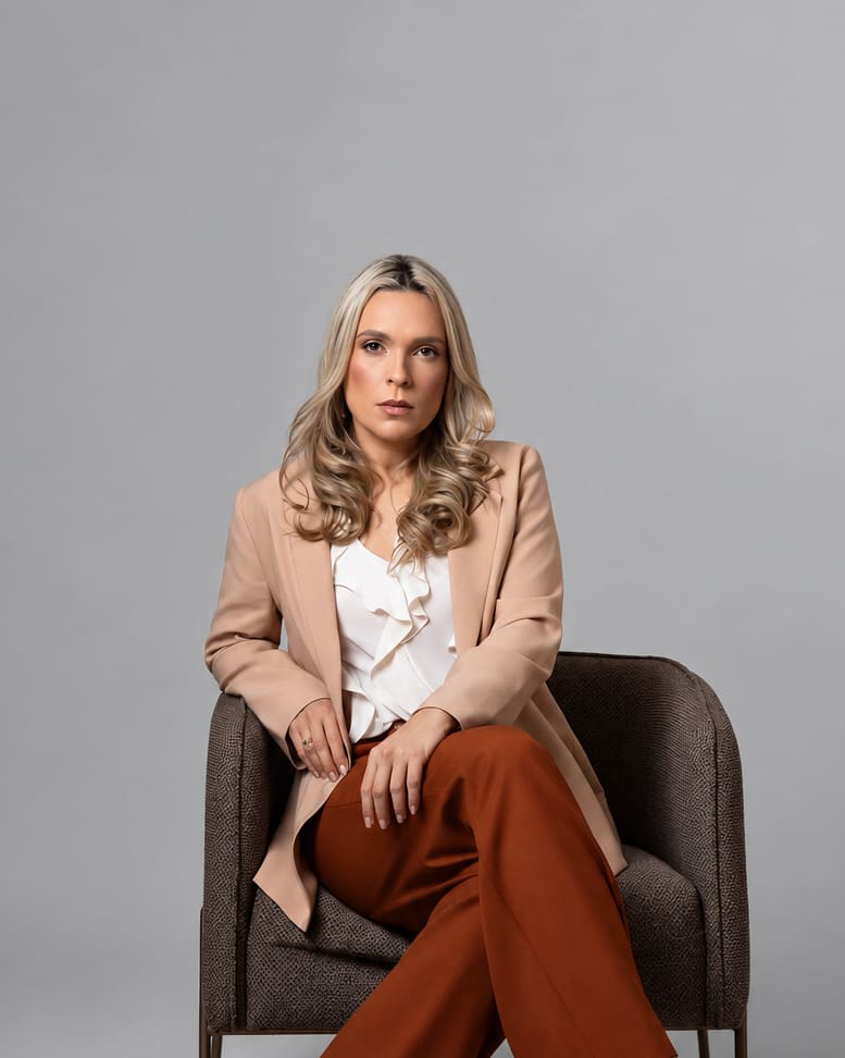 Kalina Freitas, nutricionista em Guarabira-PB, de blazer bege sentada em uma poltrona